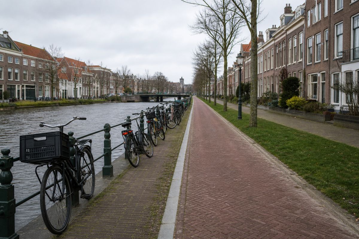 Rood klinkerfietspad langs een stadsgracht, met gewone stadsfietsen op een rij langs de leuning.